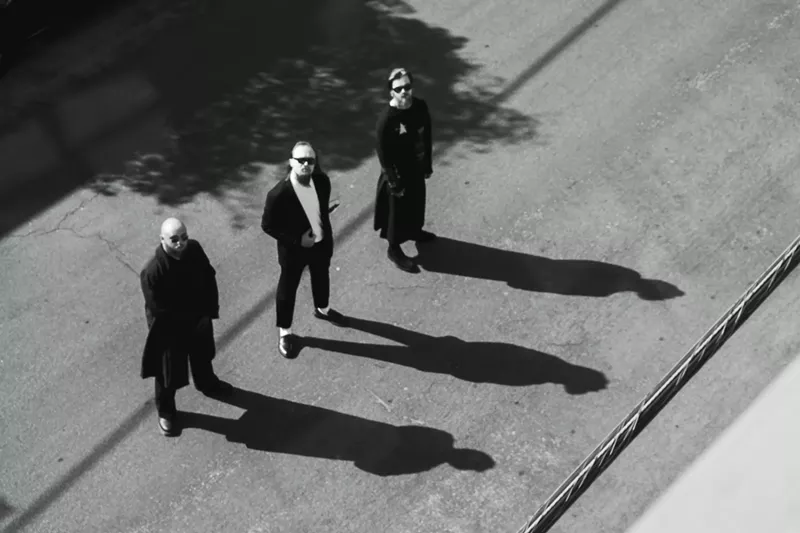 Image: three men standing in the street with their shadows
