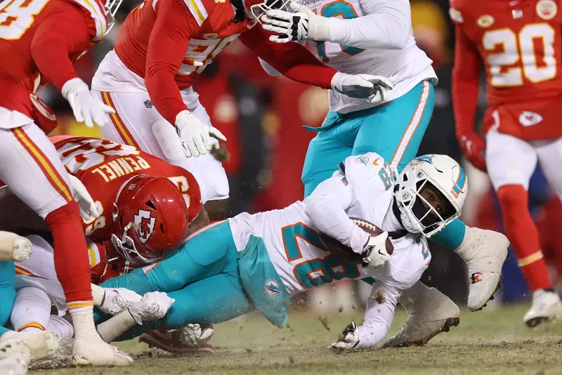 Image: Miami Dolphins running back De'Von Achane is pulled to the frozen ground in an NFL playoff game against the Kansas City Chiefs