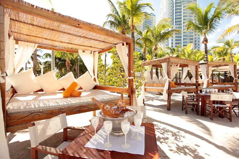 Image: wooden cabanas and white furniture at Nikki Beach, a modern dayclub in Miami Beach