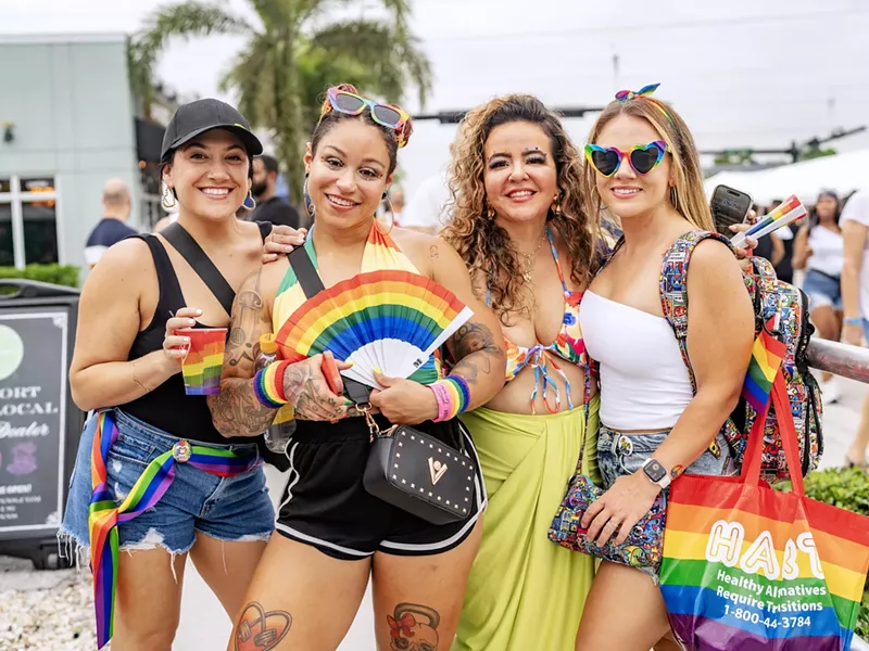 Image: four people pose for the camera at a Pride month party