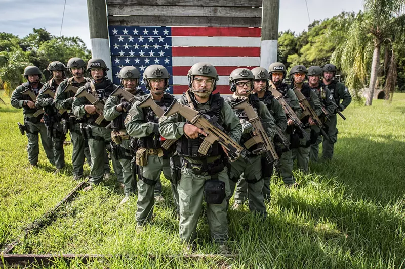 Image: Armed and uniformed U.S. Immigration and Customs Enforcement (ICE) officers standing in the grass in Miami.