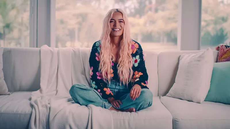 Image: A blonde woman sitting on a white couch