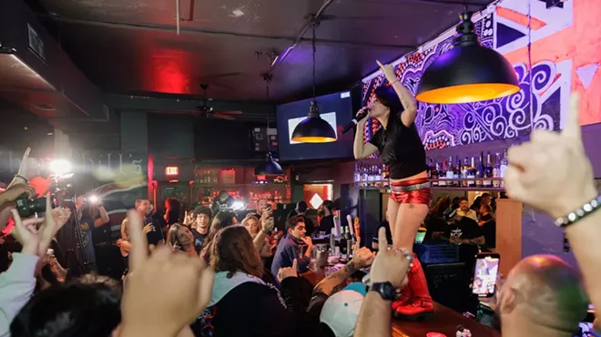 A woman singing on top of a bar surrounded by people.