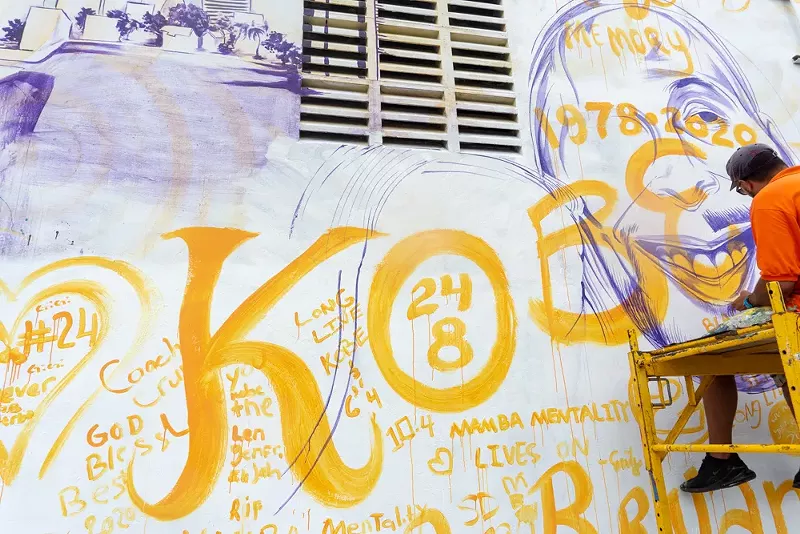 Image: Artist Kyle Holbrook paints a mural paying tribute to late basketball player Kobe Bryant.