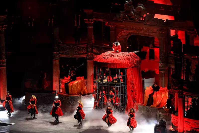 Image: Image of Lady Gaga on stage wearing a red dress that also serves as a cage.