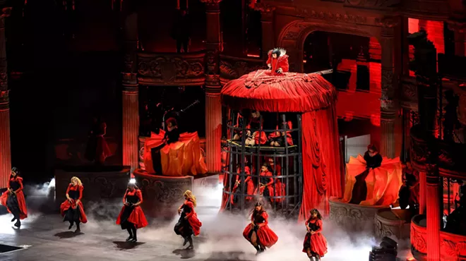 Image of Lady Gaga on stage wearing a red dress that also serves as a cage.