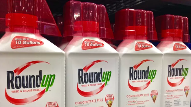 Bottles of herbicide "Roundup" sit on a shelf.