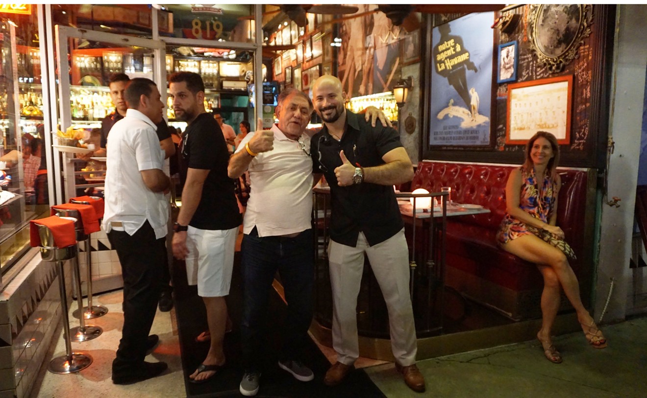 Havana 1957 manager Carlos Proenza (in black shirt and tan pants on the right) gives the thumbs-up with happy patrons.