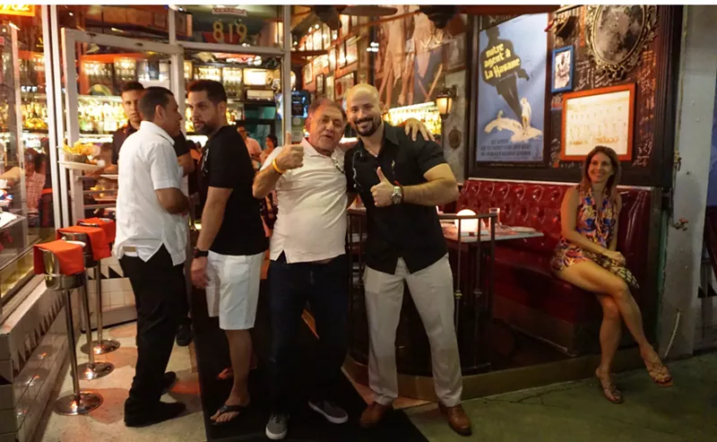 Image: Havana 1957 manager Carlos Proenza (in black shirt and tan pants on the right) gives the thumbs-up with happy patrons.