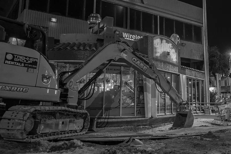 Image: A large backhoe blocks Edukos' storefront.