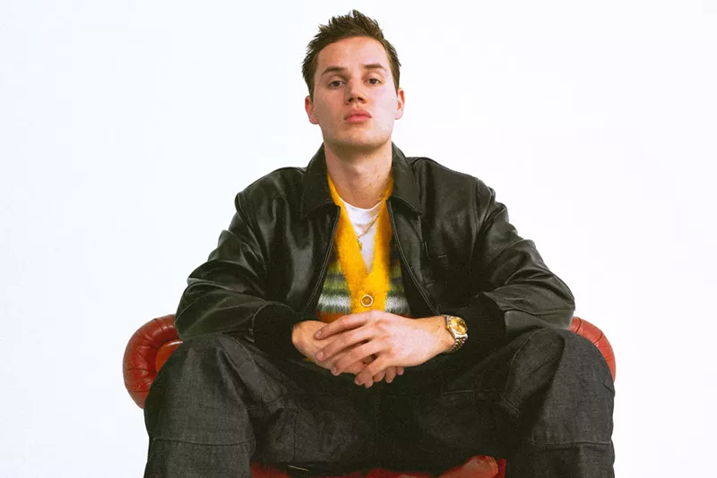 Image: Mau P sitting on a red leather chair