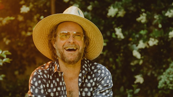 MC Taylor of Hiss Golden Messenger smiling and wearing a straw hat