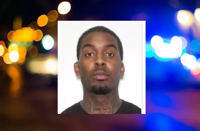 Image: Booking photo of a man with neck tattoos staring blankly into camera