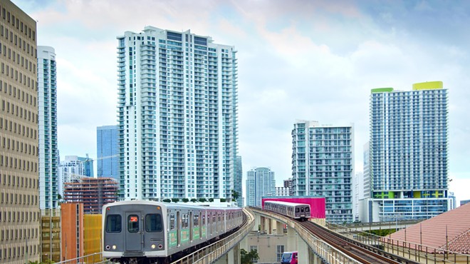 Two metro trains on elevated platforms with the Miami skyline in the background