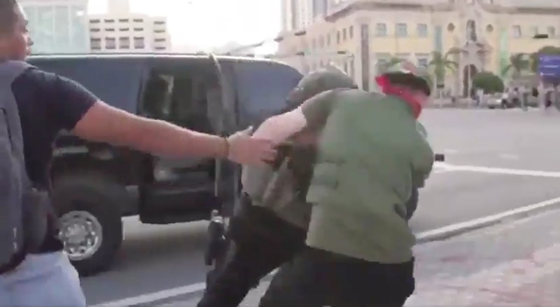 Miami-Dade police Officer Roberto De la Nuez grabs protester Ariel Alfaro-Fonseca.