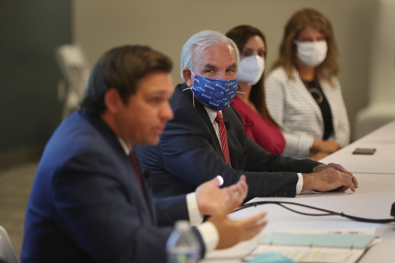 Miami-Dade Mayor Carlos A. Gimenez (center) listens as Florida Gov. Ron DeSantis (left) speaks during a July 7 press conference in Miami.