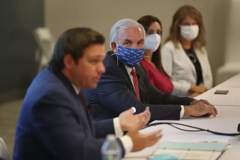 Image: Miami-Dade Mayor Carlos A. Gimenez (center) listens as Florida Gov. Ron DeSantis (left) speaks during a July 7 press conference in Miami.