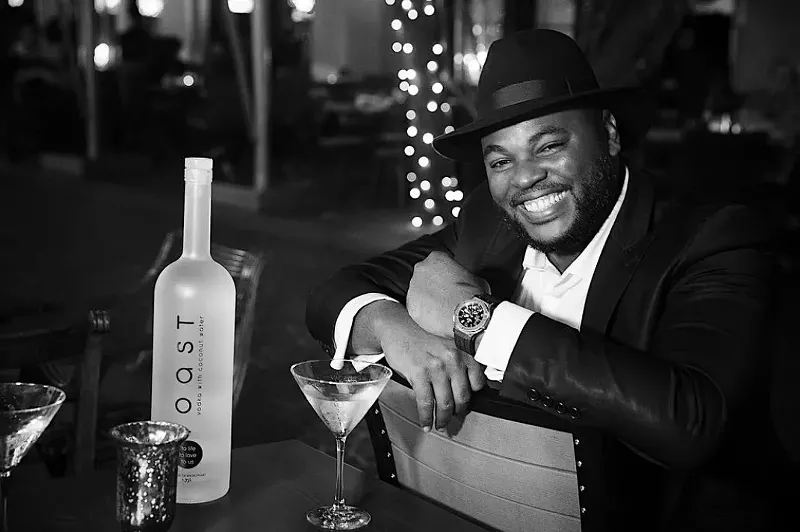 Image: Founder and CEO of Toast Distillers Dieuveny "DJ" Jean Louis smiles next to his award-winning product.