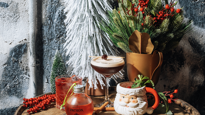 A group shot of holiday cocktails made with Patron. The drinks sit on a wooden stool surrounded by holiday decor.