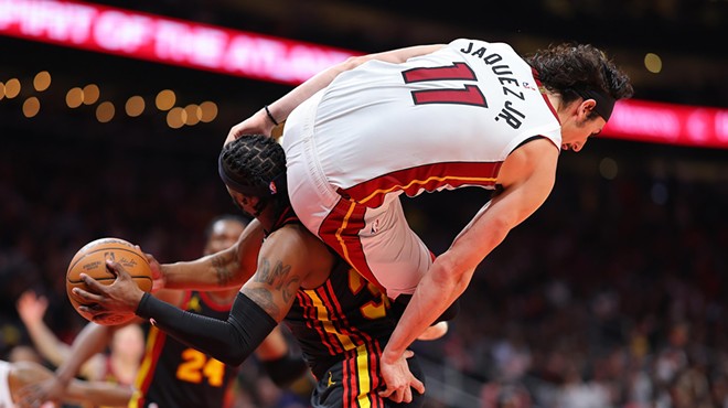 Jaime Jaquez of the Miami Heat is careening in the air during a game, with his derriere positioned on the neck of an Atlanta Hawks player