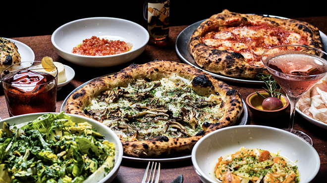 an array of dishes and pizzas on a wood table