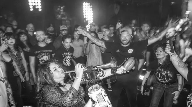 Black and white picture of people dancing around a trumpet player.
