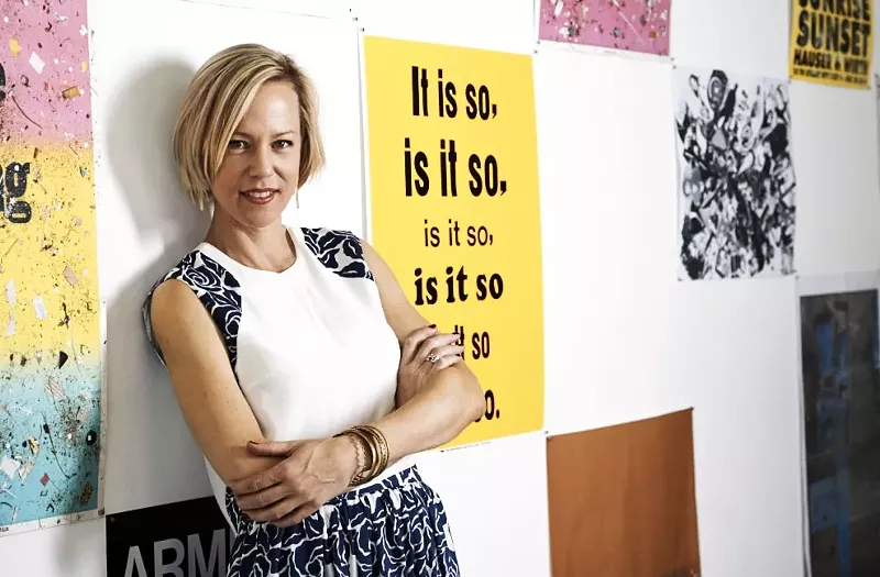 Image: a woman stands in front of a wall of posters