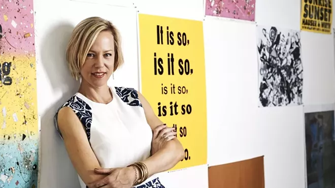a woman stands in front of a wall of posters