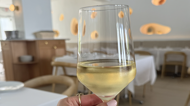 A glass of white wine in a naturally lit restaurant