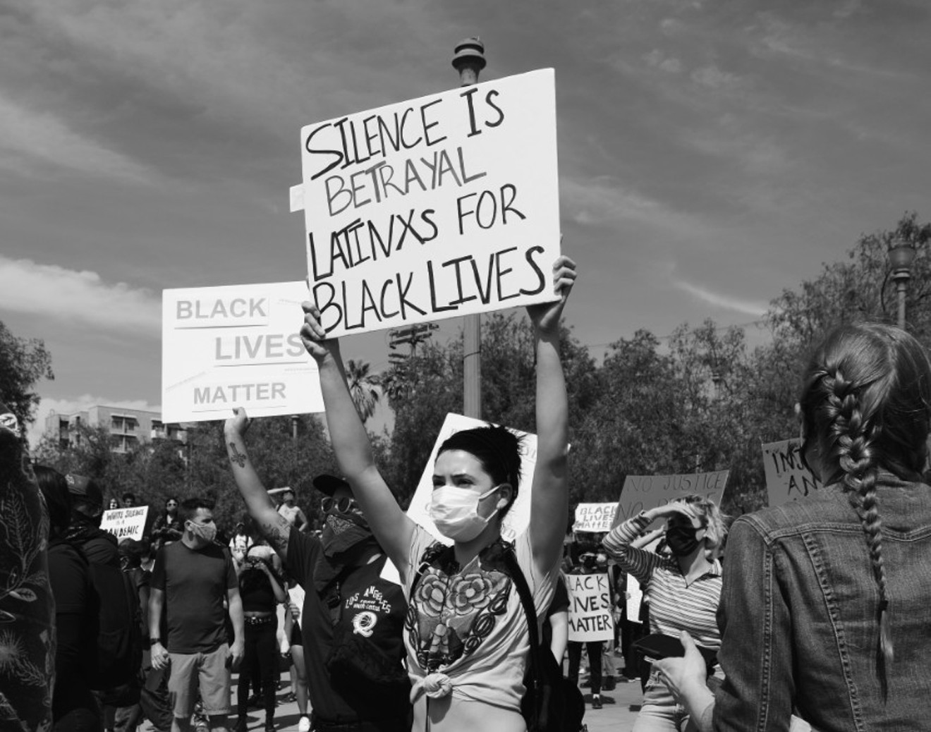 A protester holds up a sign showing Latino solidarity with BLM.
