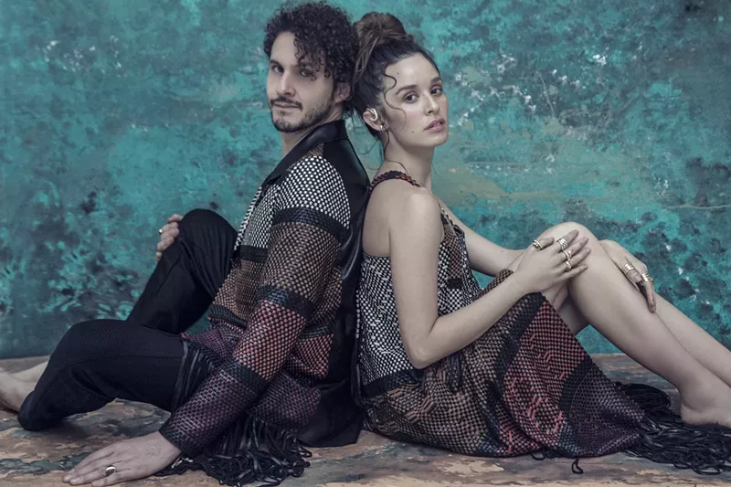 Image: the two members of monsieur perine sitting back to back