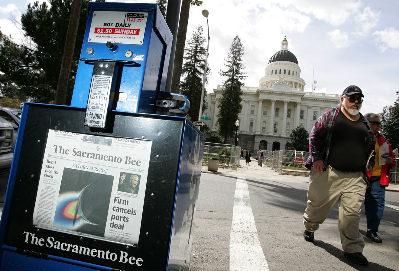 A man walks by a Sacramento Bee newspaper rack across from the California State Capitol in Sacramento, California.