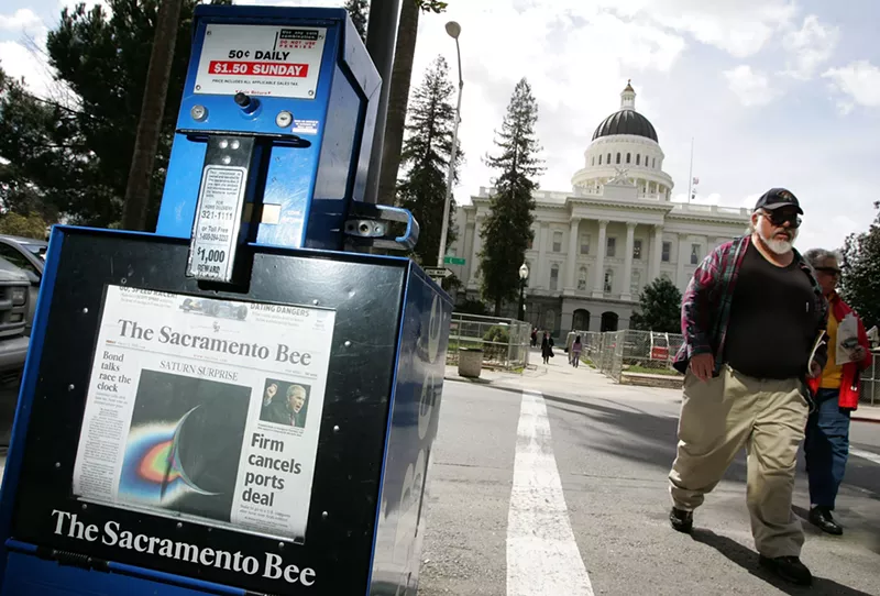 Image: A man walks by a Sacramento Bee newspaper rack across from the California State Capitol in Sacramento, California.