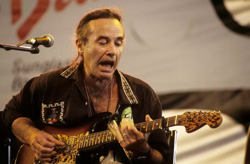 Image: Ry Cooder performing on stage with a guitar in hand