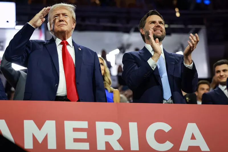 Image: Donald Trump saluting the crowd at the RNC in Milwaukee as J.D. Vance stands beside him applauding
