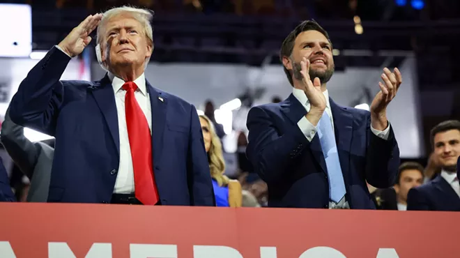 Donald Trump saluting the crowd at the RNC in Milwaukee as J.D. Vance stands beside him applauding