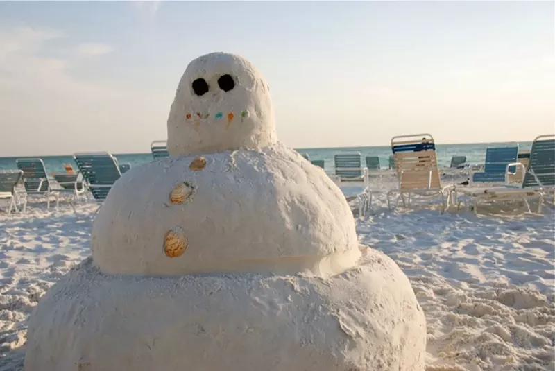 Image: photo of a snowman made out of sand on a a beach