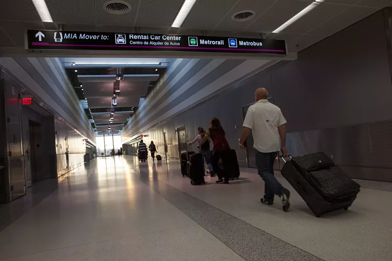 Image: Travelers haul luggage through Miami International Airport.