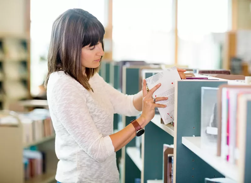 Image: stock photo of a woman shelving books in a library