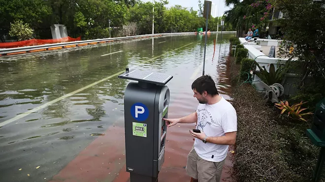 Man pays for parking at pay by phone meter on a flooded street