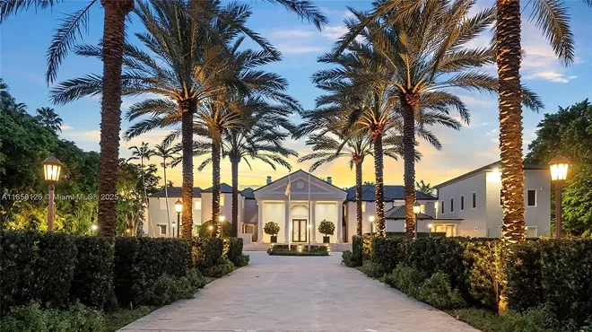 A brick driveway is pictured in the foreground leading to a luxe mansion in Miami Beach.