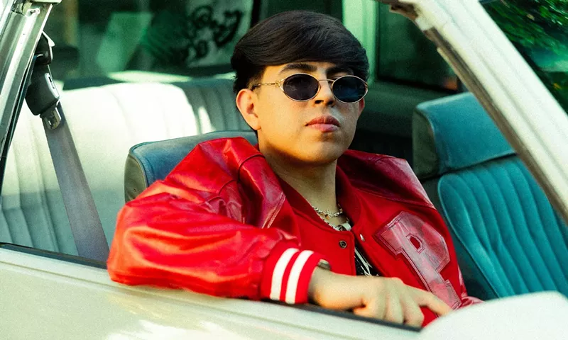 Image: Picture of a young Latin man inside a convertible car wearing sunglasses