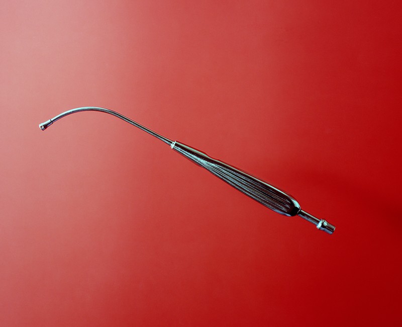 Tony Chirinos’s exhibit “The Precipice” at the University of Miami Art Gallery features photographs of surgical tools, like this Yankauer suction tube, suspended against bright-colored backgrounds.