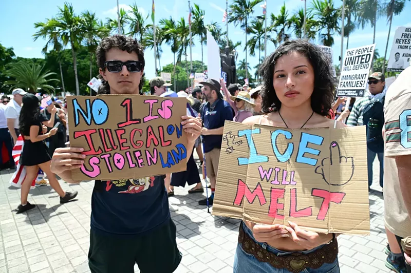 Image: two protesters hold up painted signs reading "no 1 is illegal on stolen land" and "ICE will melt"