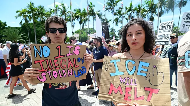 two protesters hold up painted signs reading "no 1 is illegal on stolen land" and "ICE will melt"
