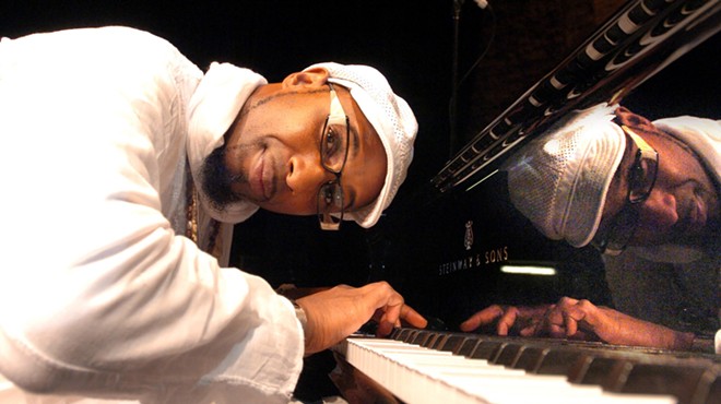 Omar Sosa leaning over the keys of his piano while looking at the camera