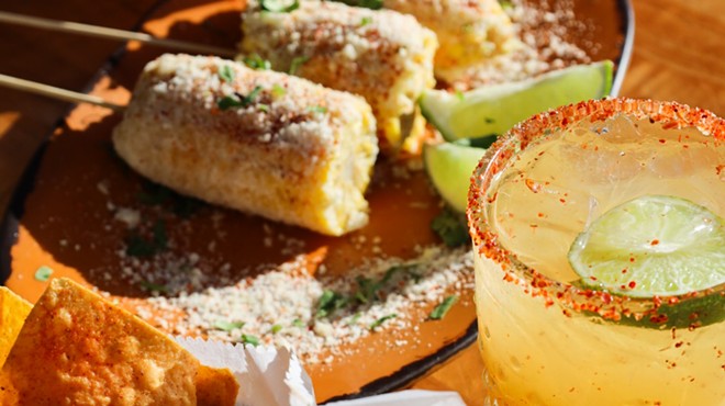 A cocktail and elotes corn on a table