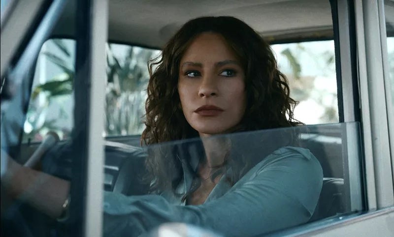 Image: Still from Episode 1 of Griselda, showing Sofía Vergara as Griselda Blanco, at the wheel of a 1960s or '70s-era car.