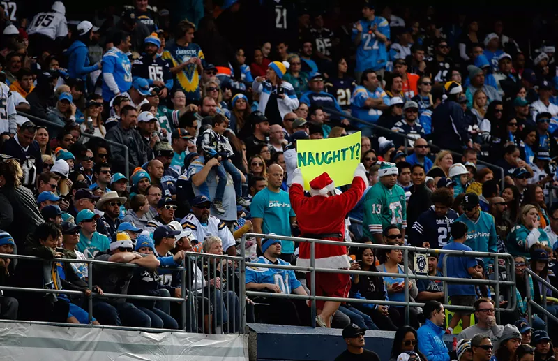 Image: A man dressed as Santa Claus walks through Qualcomm Stadium with a sign during a game between the San Diego Chargers and Miami Dolphins.