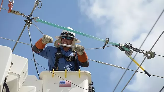 A utility employee works on a power line.